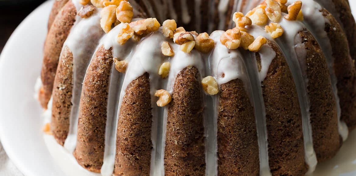 Pear Walnut Bundt Cake with glaze and garnished with walnuts on a serving platter.