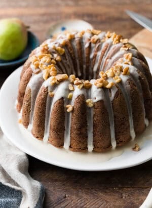 Pear Walnut Bundt Cake with glaze and garnished with walnuts on a serving platter.