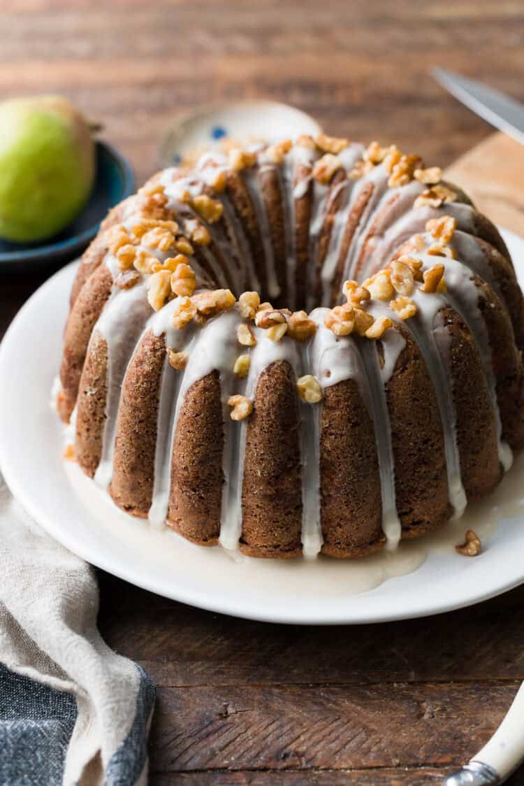 Pear Walnut Bundt Cake with glaze and garnished with walnuts on a serving platter.