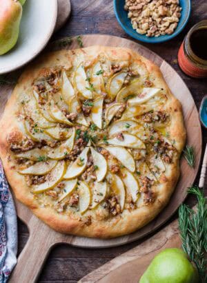 Pear, Walnut, and Gorgonzola Pizza drizzled with honey on a wooden board.