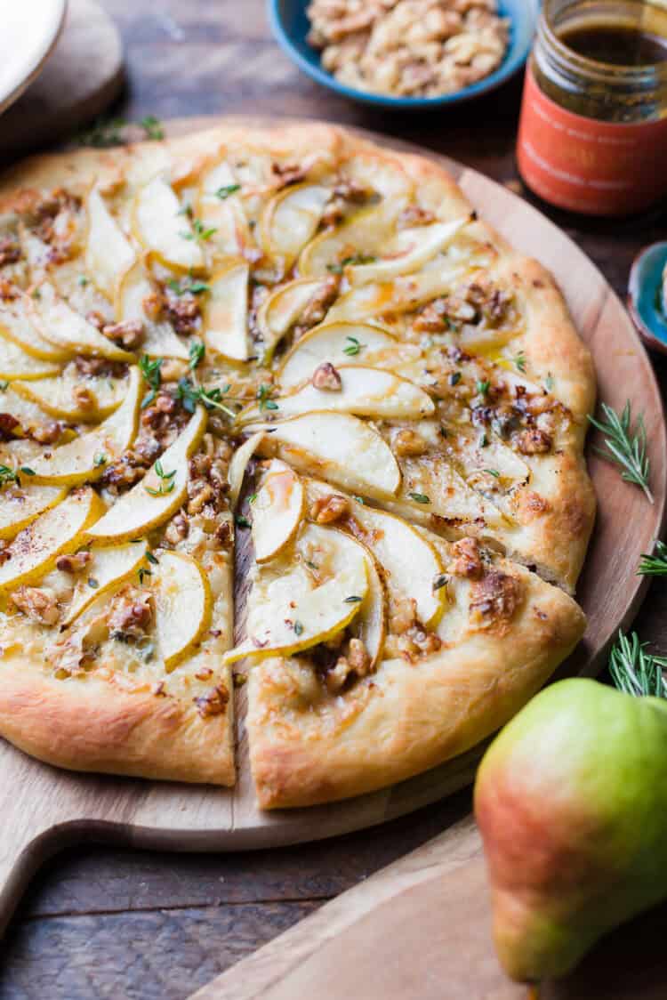 Pear, Walnut and Gorgonzola Pizza, sliced in a wooden cutting board.