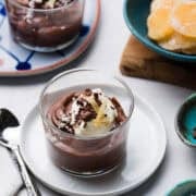 Coconut Chocolate Pudding in a serving glass, garnished with chocolate curls, crystalized ginger, and shredded coconut.