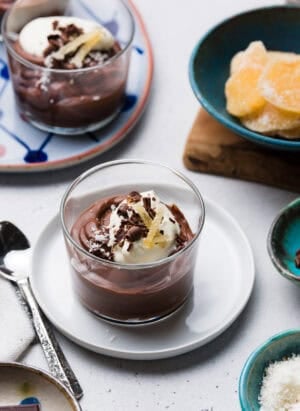 Coconut Chocolate Pudding in a serving glass, garnished with chocolate curls, crystalized ginger, and shredded coconut.