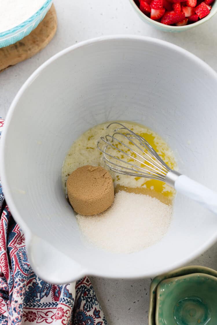 Whisking melted butter, granulated sugar, and brown sugar in a bowl.