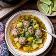 Albondigas (Mexican meatball soup) in a bowl: beef meatballs with potatoes, chayote, zucchini, and fresh herbs.