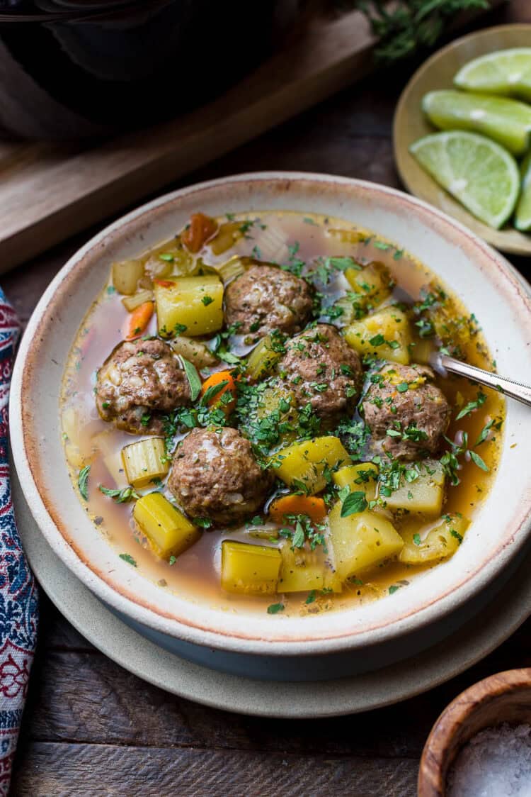 Albondigas (Mexican meatball soup) in a bowl: beef meatballs with potatoes, chayote, zucchini, and fresh herbs.