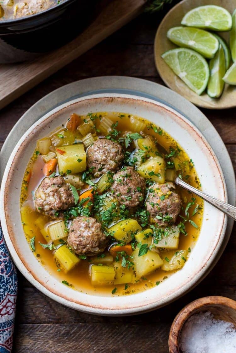 Albondigas (Mexican meatball soup) in a bowl: beef meatballs with potatoes, chayote, zucchini, and fresh herbs.