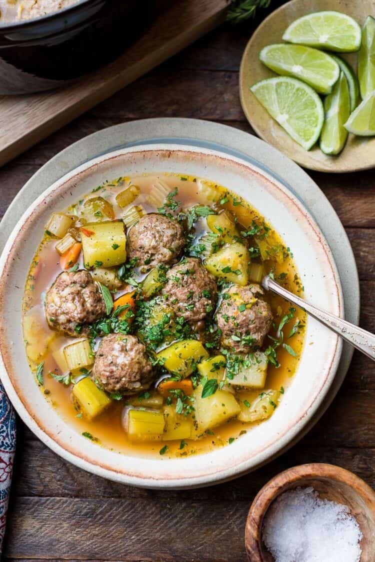 Albondigas (Mexican meatball soup) in a bowl: beef meatballs with potatoes, chayote, zucchini, and fresh herbs.