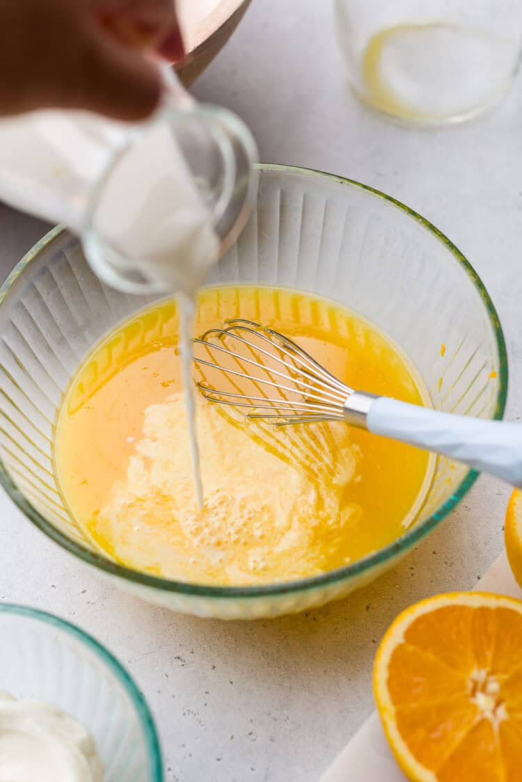 Adding milk to orange juice for an orange sherbet recipe.