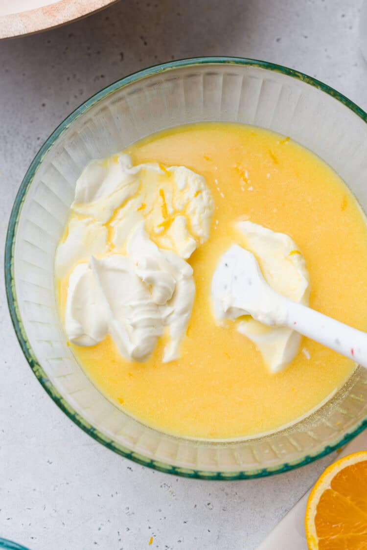 Folding whipped cream into an orange sherbet base.