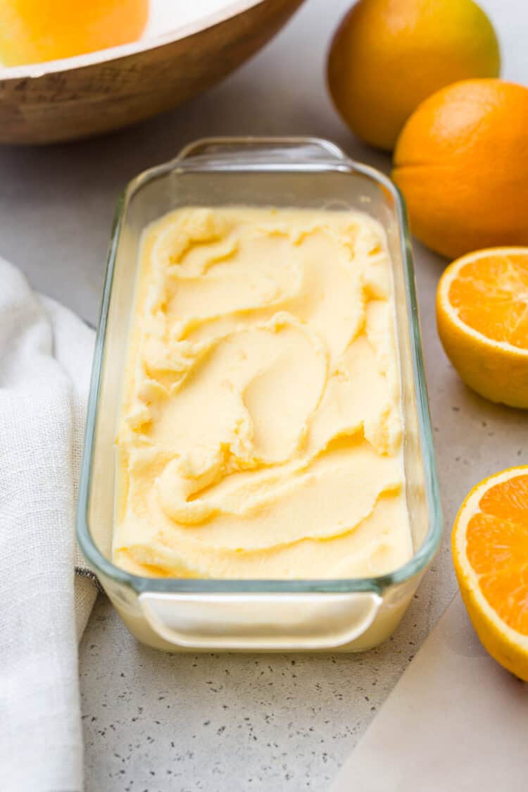 Freshly churned orange sherbet in a glass dish.