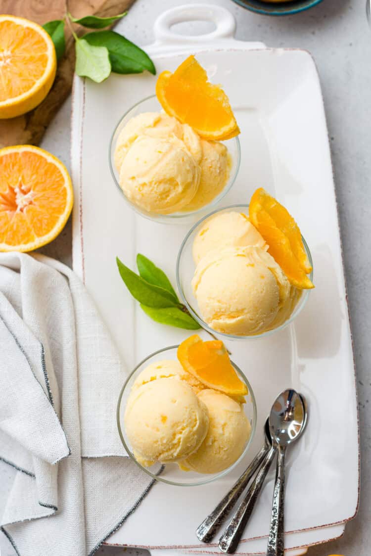 Glass dishes with orange sherbet, garnished with orange slices.