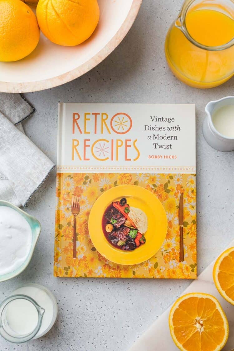 Retro Recipes cookbook by Bobby Hicks surrounded by ingredients for orange sherbet.